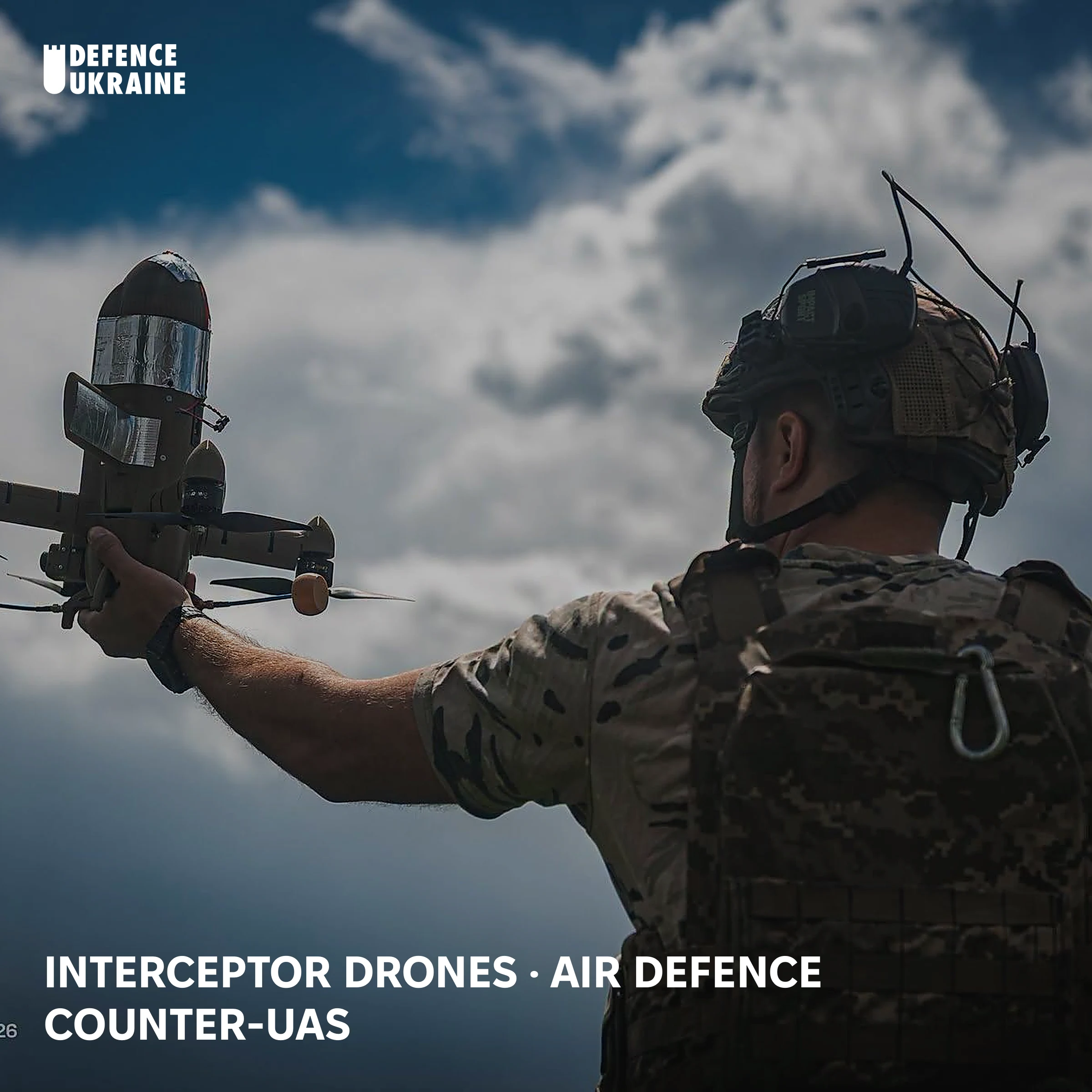 A Ukrainian soldier of the 114th Territorial Defence Brigade raises a Sting interceptor drone before launch against a cloudy sky, the cheap drone-hunter used against Russian Shahed and Geran-4 strike drones.