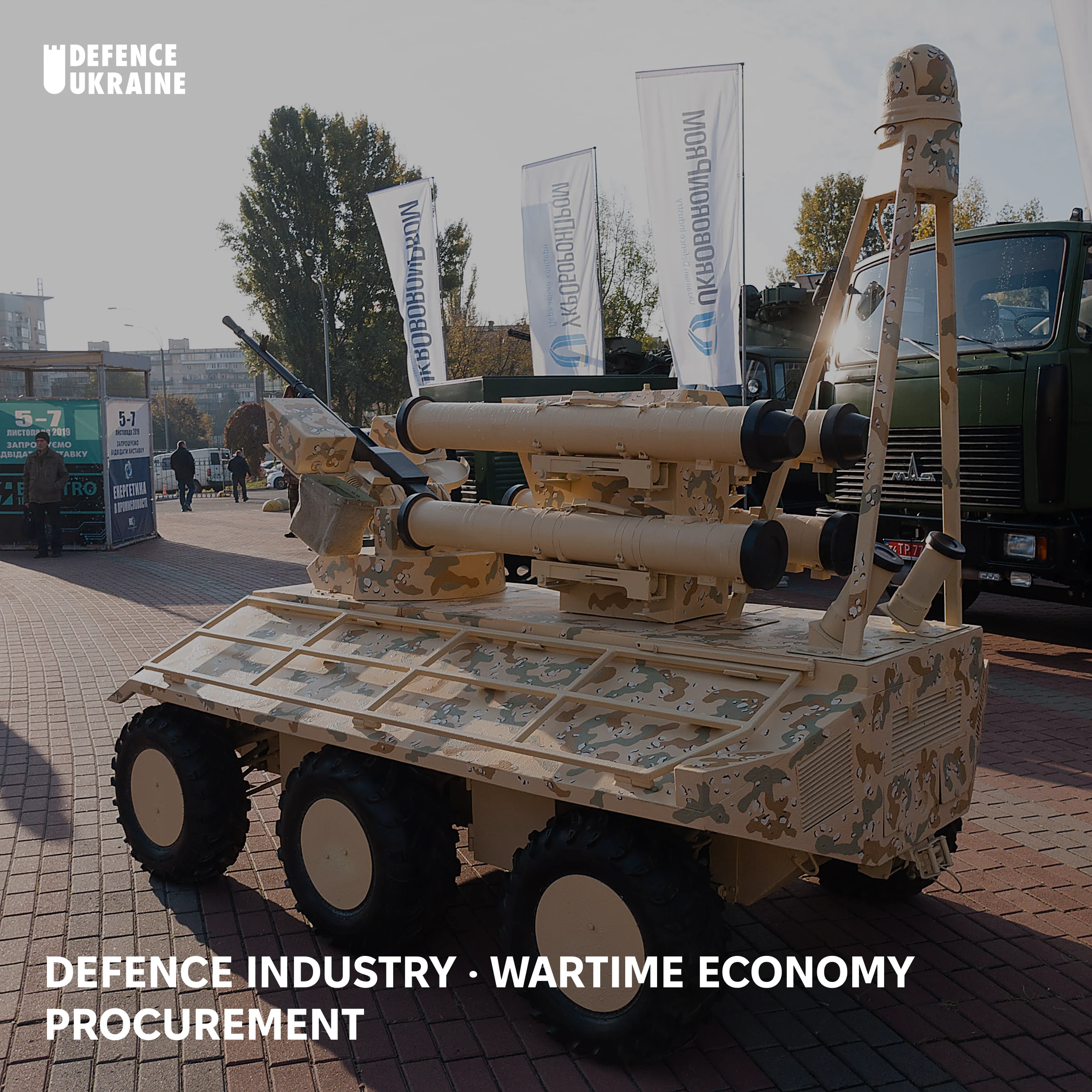 A six-wheeled Ukrainian Phantom unmanned ground vehicle mounted with recoilless guns, displayed beside Ukroboronprom banners at the Zbroya ta Bezpeka defence exhibition in Kyiv, illustrating Ukraine's exportable defence-industrial output.