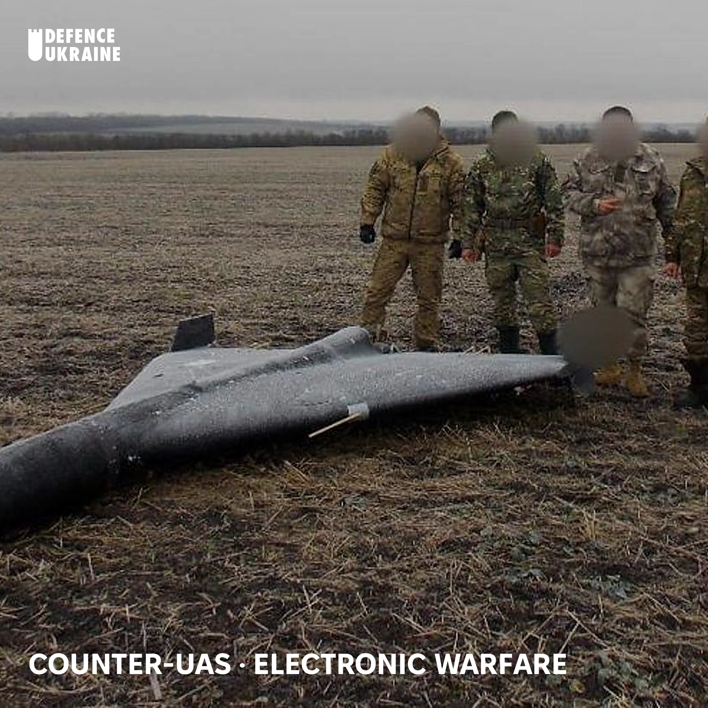Ukrainian soldiers stand over a downed Iranian-designed Shahed loitering munition in a field, one of hundreds of Russian one-way attack drones neutralised during the defence of Ukrainian cities.